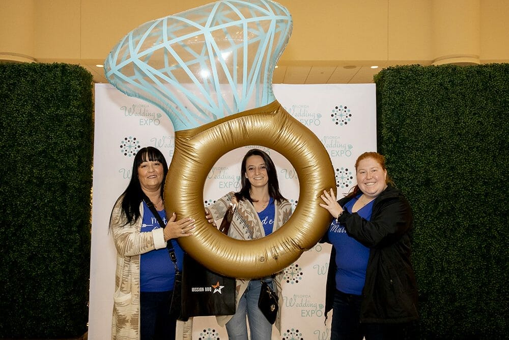 Women posing with inflatable wedding ring